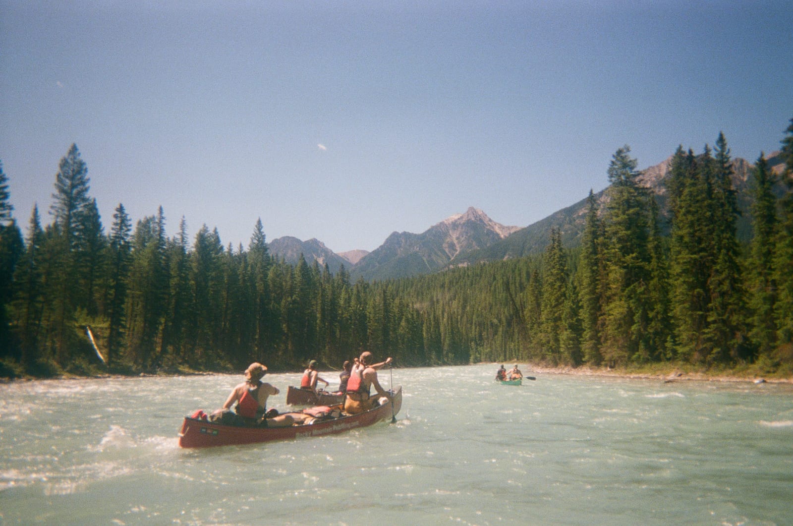 Loaded canoes gliding along the turquoise Kootenay River in British Columbia